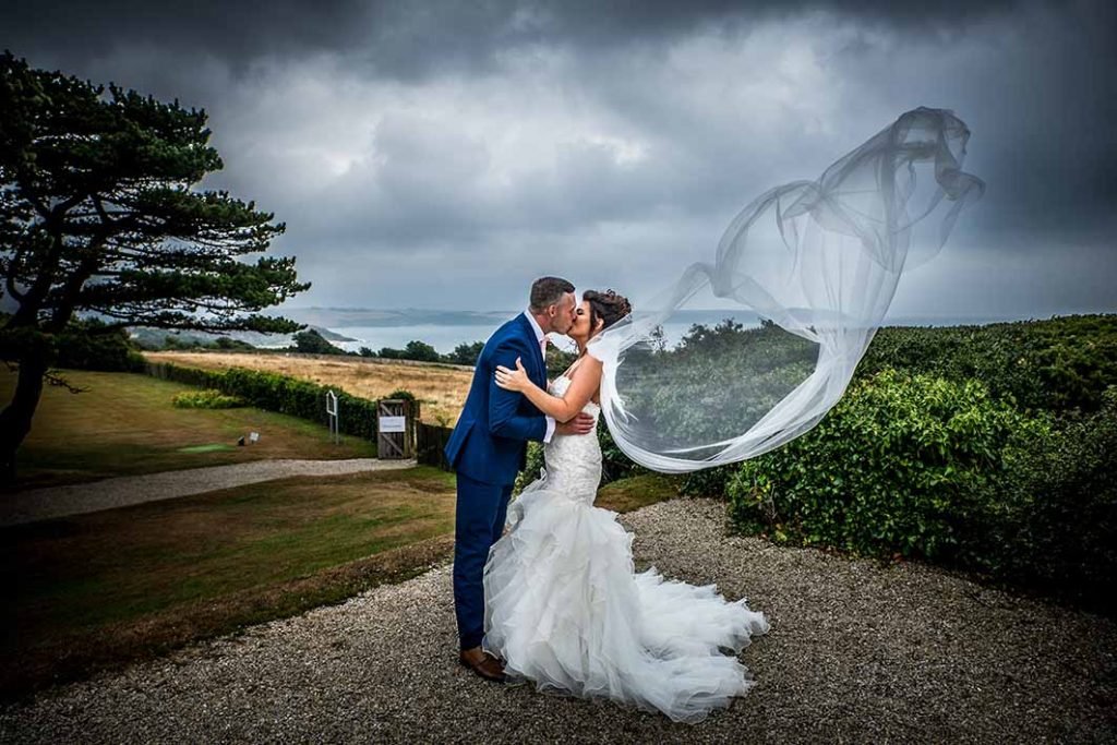 bride and groom kissing in the gardens at The carlyon Bay Hotel Cornwall dramatice veil shot