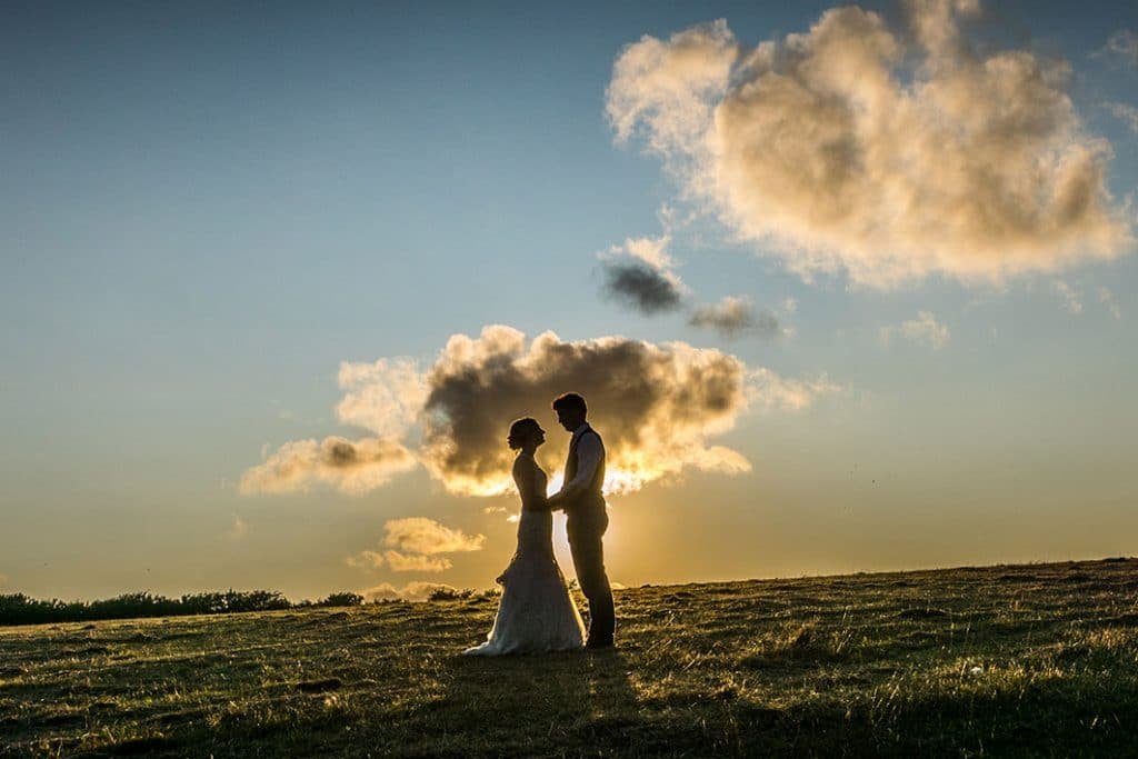 bride and groom holding hands at sunset at Trenderway Farm cornwall