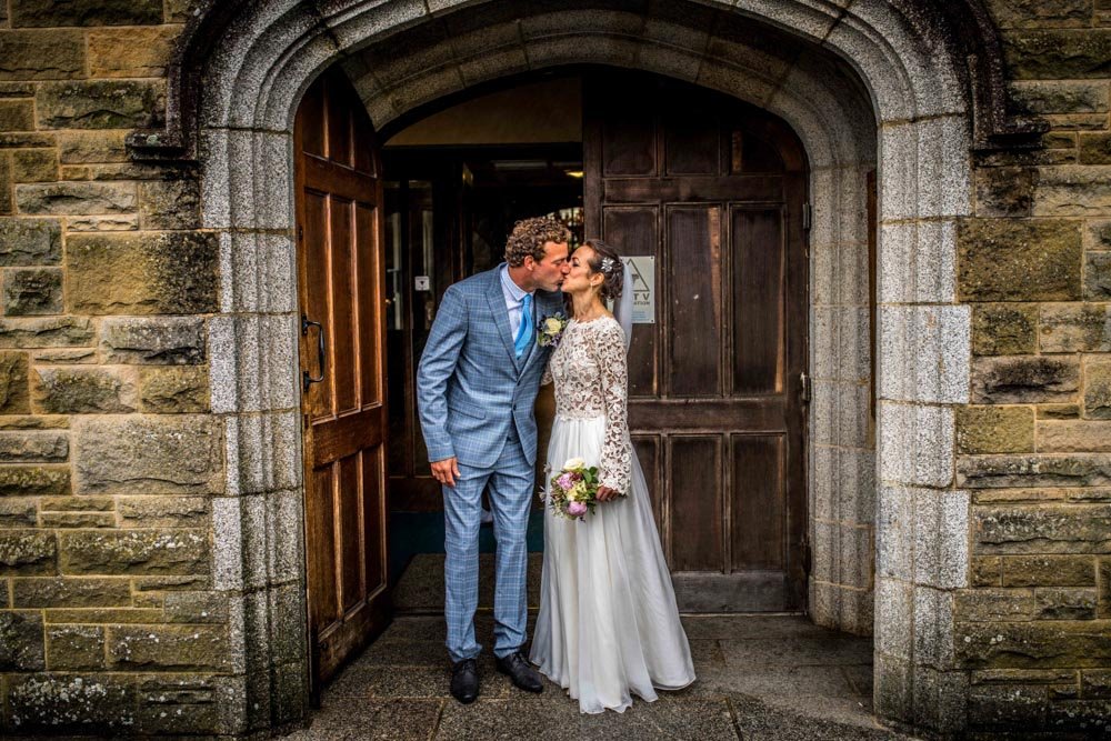 bride and groom kissing in the church doorway