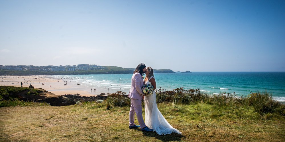 bride and groom kissing on the coast path above fistral beach cornwall