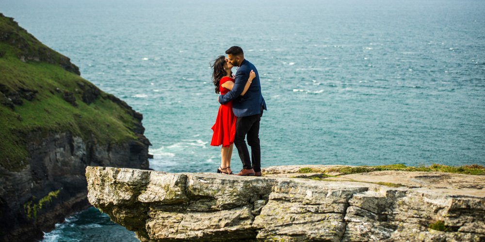 couple kissing on a rock overlooking Tintagel castle cornwall