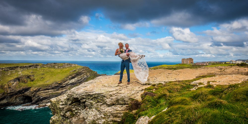 groom carrying the bride on the coast path at Tintagel castle Cornwall