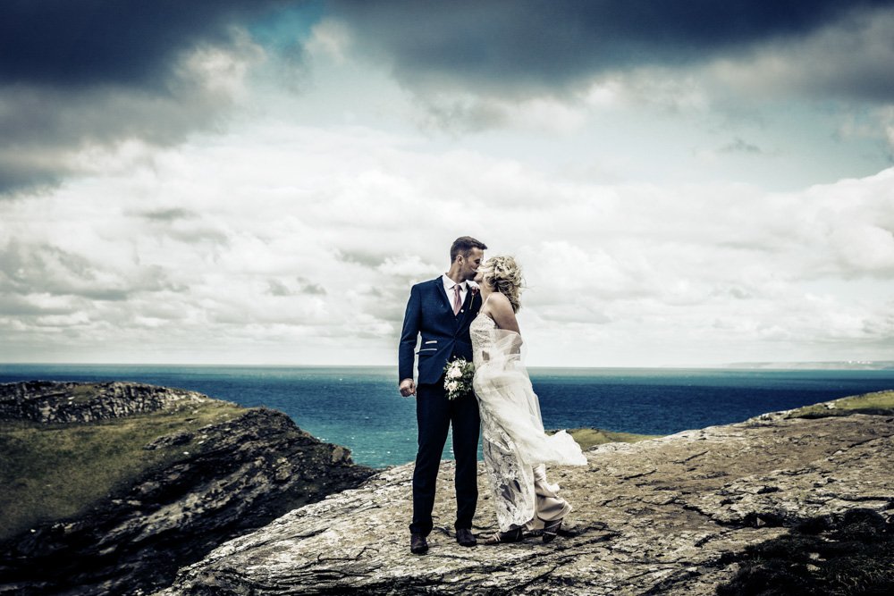 bride and groom kissing on the coast path at Tintagel castle Cornwall modern antique