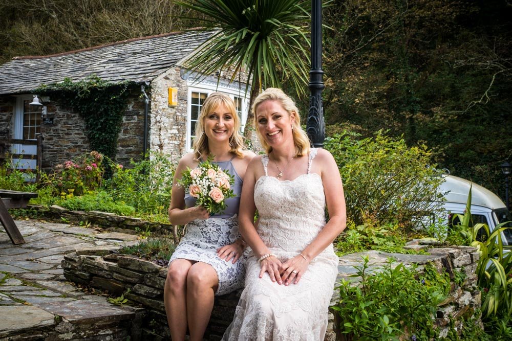 bride and bridesmaid sitting on a wall
