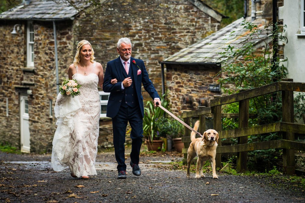 bride and father walking with dog to the wedding ceremony
