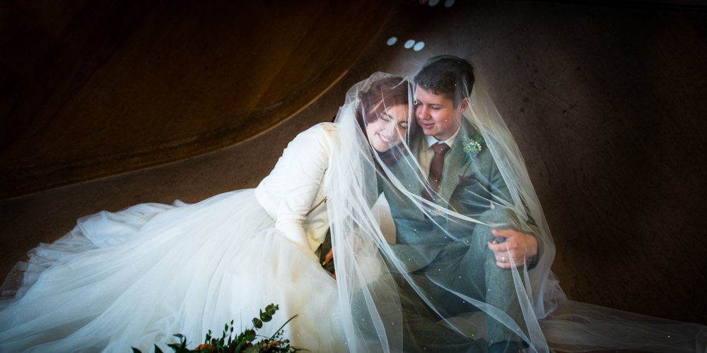 Bride and groom embrace under a floral arch