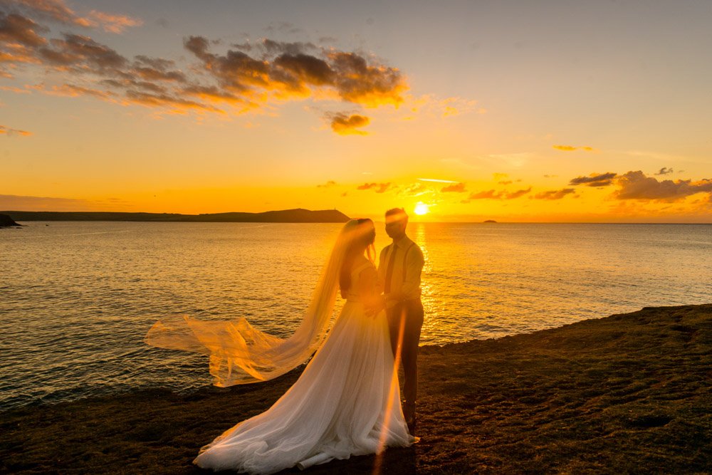 bride and groom kissing at sunset Polzeath cornwall