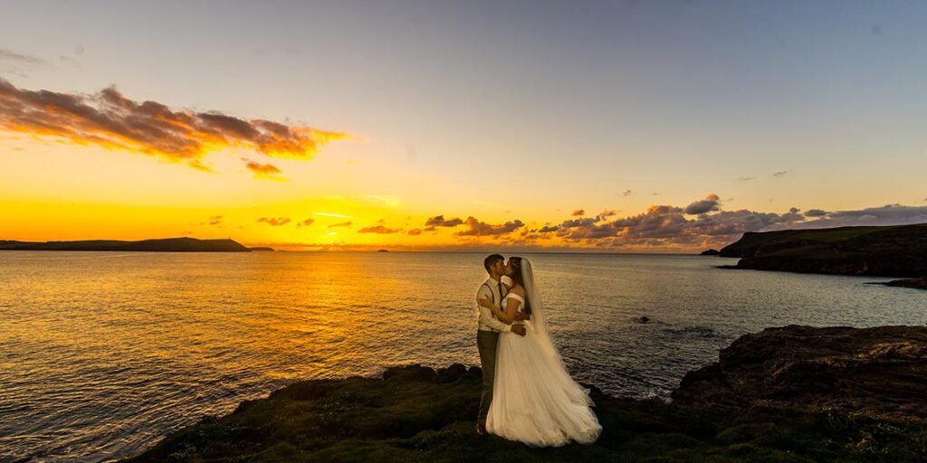 bride and groom kissing at sunset on Polzeath Beach Cornwall