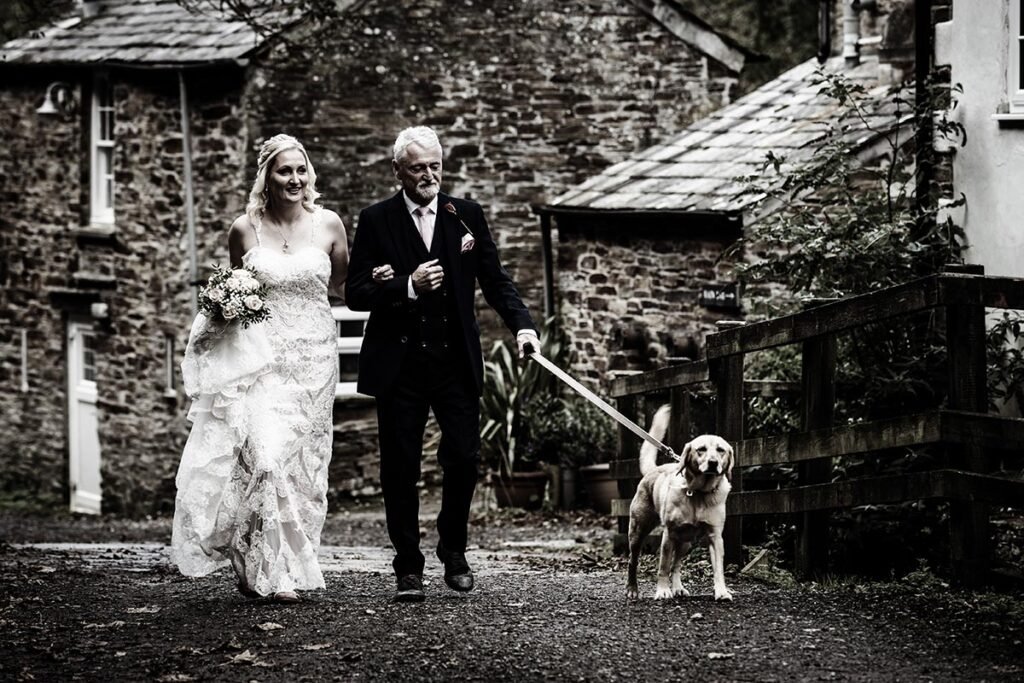 bride and father with dog arriving for the wedding ceremony B&W