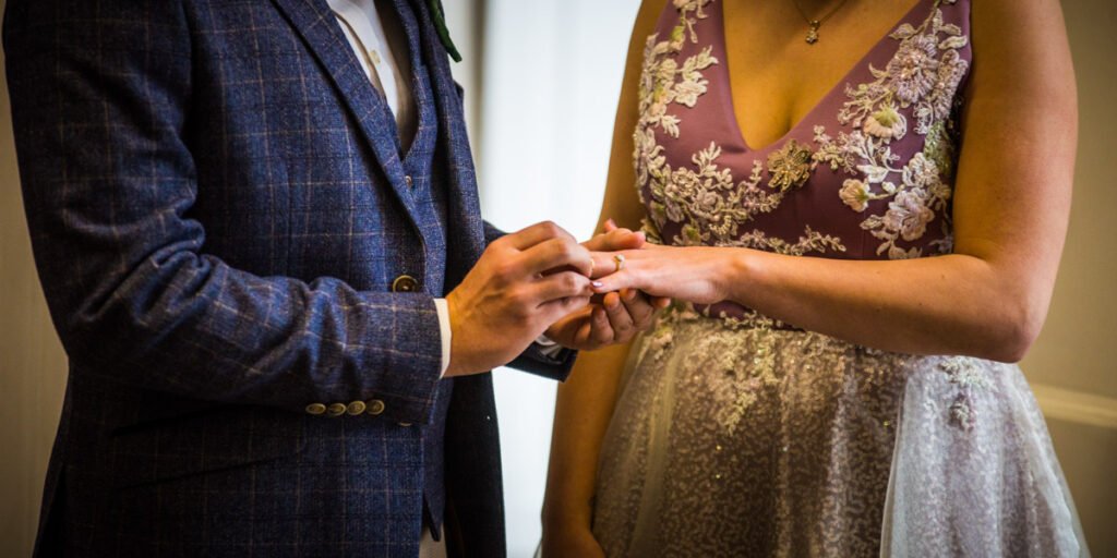 bride and groom exchanging rings at Cockington country park Devon