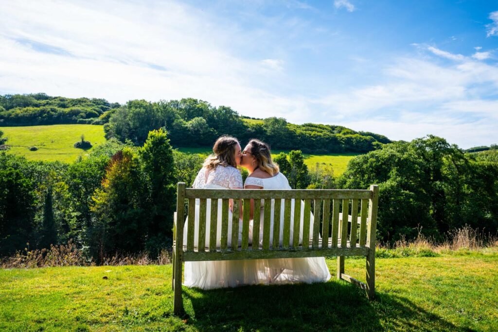 bride and bride on a bench in the garden at Pengenna Manor Cornwall