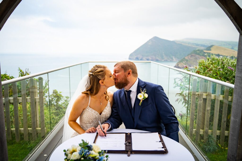 bride and groom kissing and signing at devon wedding venue The Sandy cove hotel