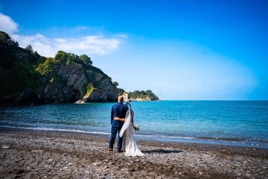 bride and groom looking out to sea at devon wedding venue The Sandy cove hotel