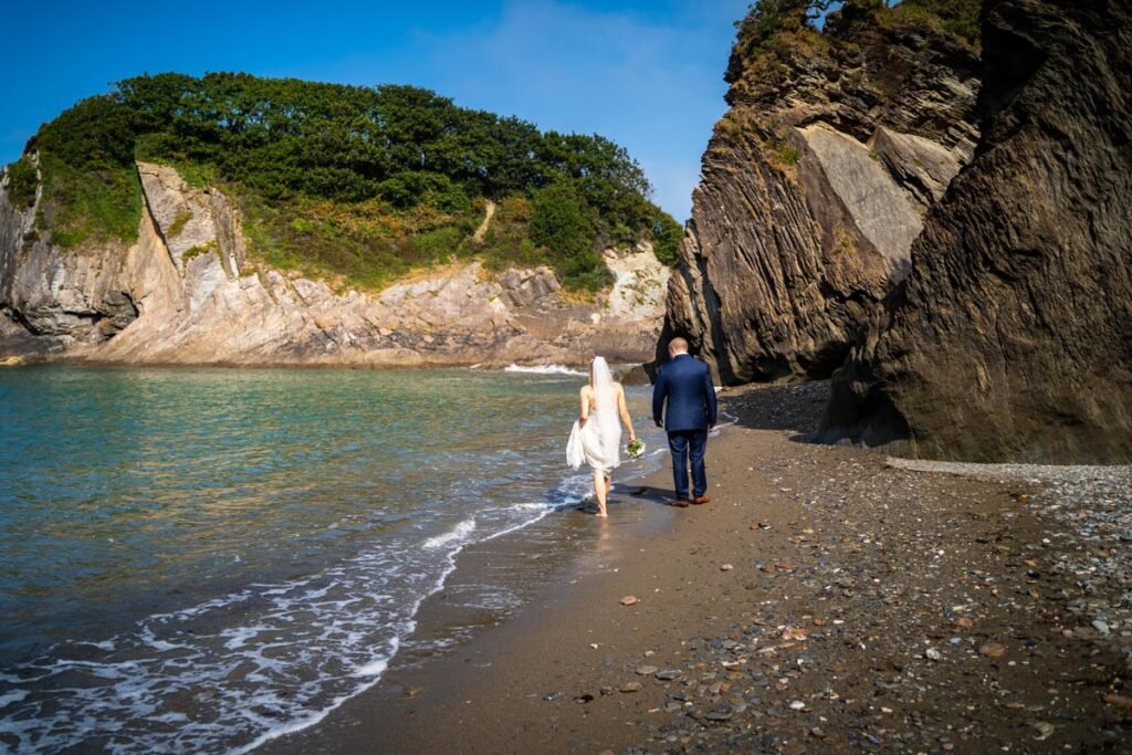 bride and groom on the beach walking away at devon wedding venue The Sandy cove hotel