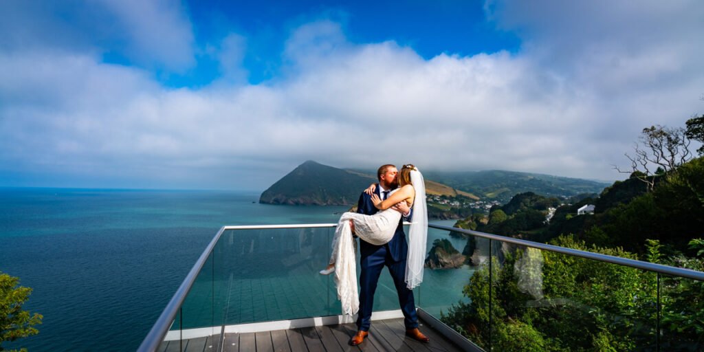 groom carrying the bride at devon wedding venue The Sandy cove hotel sea veiw