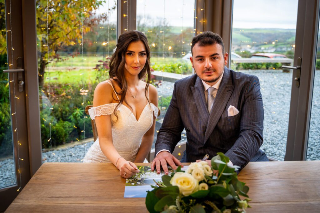 bride and groom signing the register at Trevenna Barns Cornwall