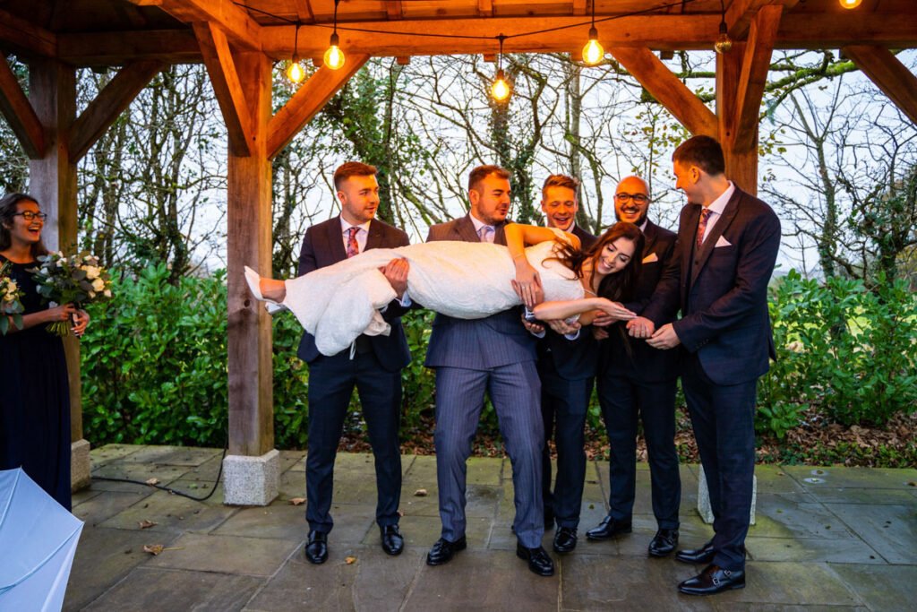 Bride being carried by the groomsmen at Trevenna Barns Cornwall