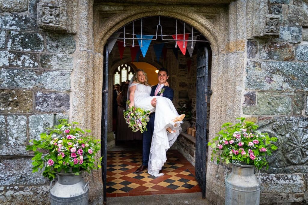 bride carrying groom in the church doorway