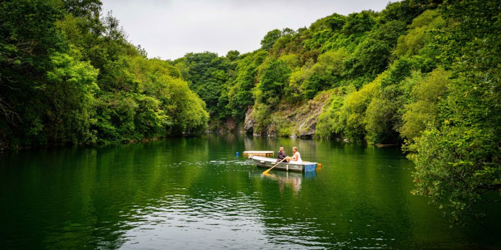 bride and groom rowing boat on the lake at cornish tipis in cornwall