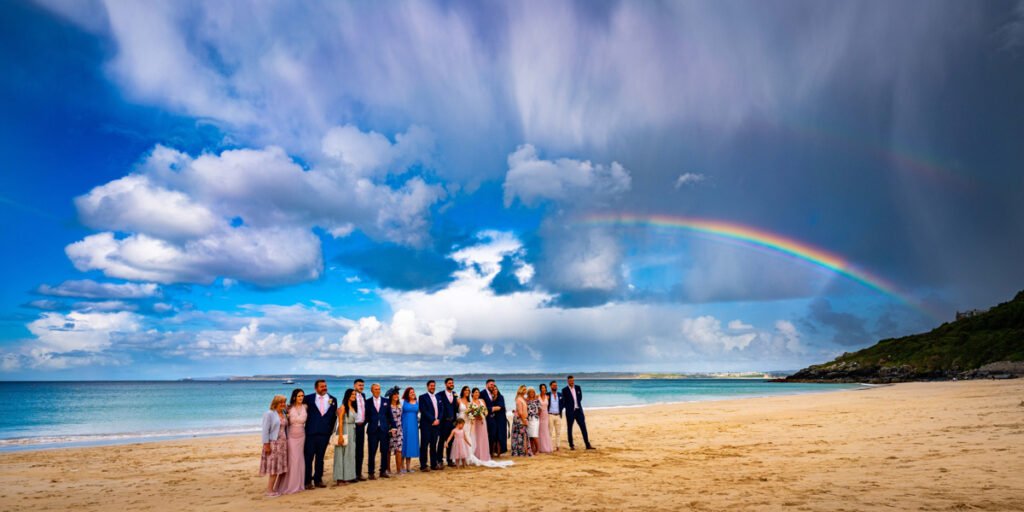 wedding group shot with rainbow on Porthminister beach St Ives