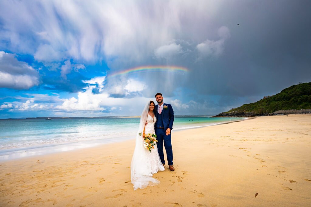 bride and groom on Porthminister beach St Ives with a rainbow