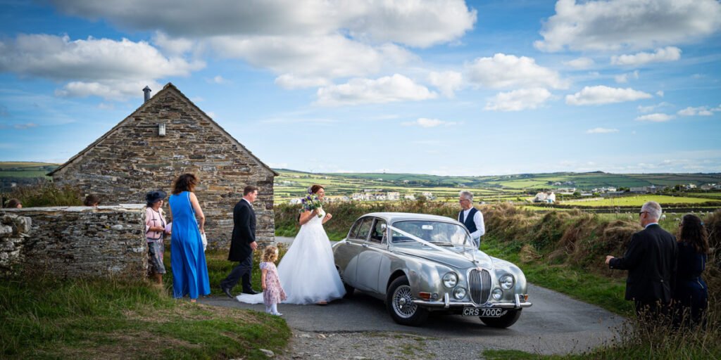 bridal party with the wedding car outside church