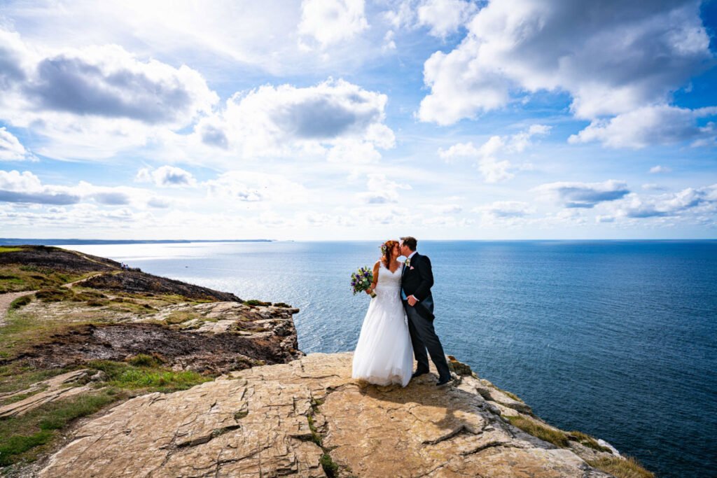 Bride and groom on the cliff overlooking port isaac bay cornwall