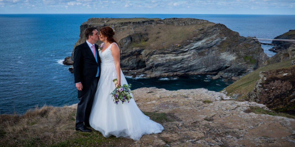 Bride and groom on the cliff overlooking tintagel island