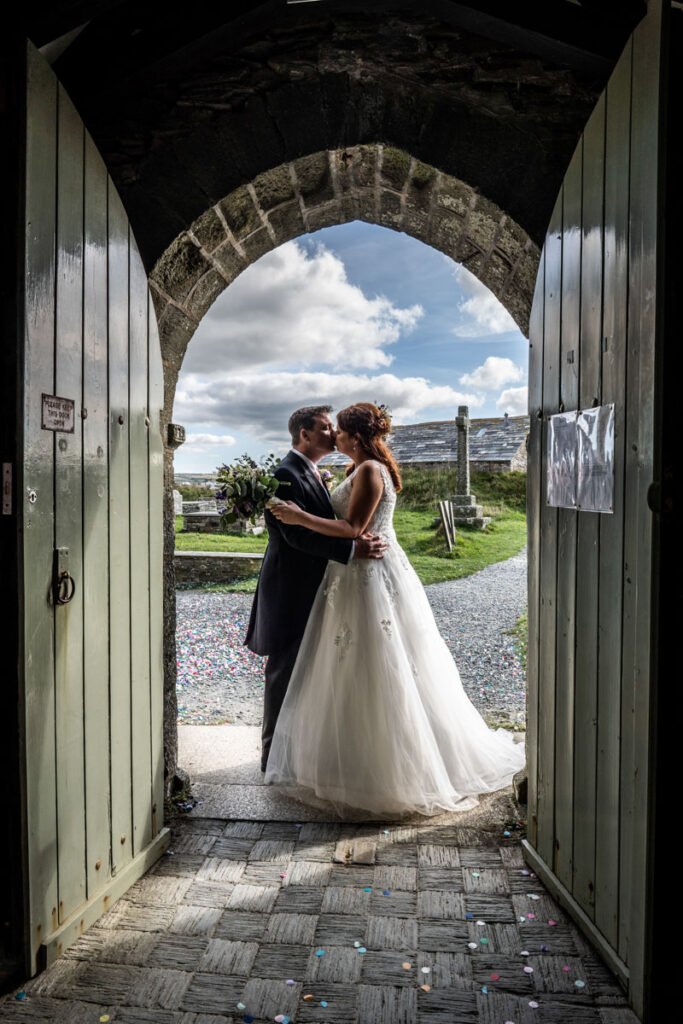 Bride and groom in the chuch doorway in Tintagel cornwall