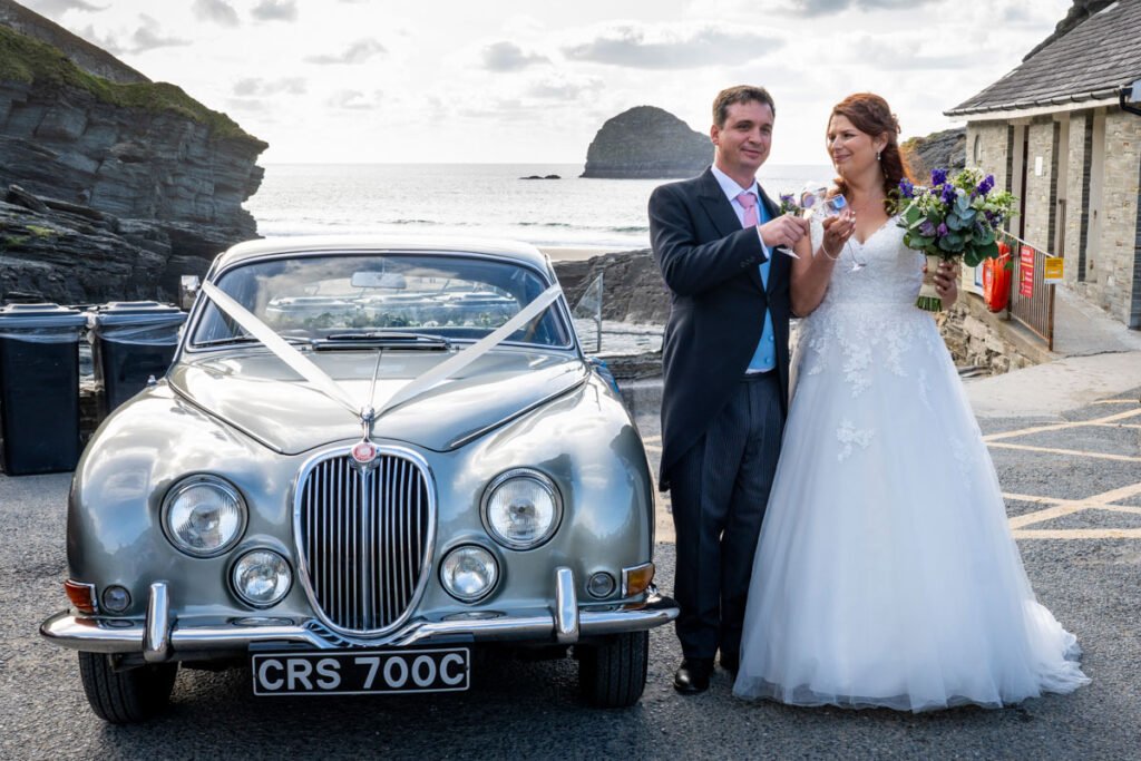 bride and groom with wedding car at the beach in cornwall