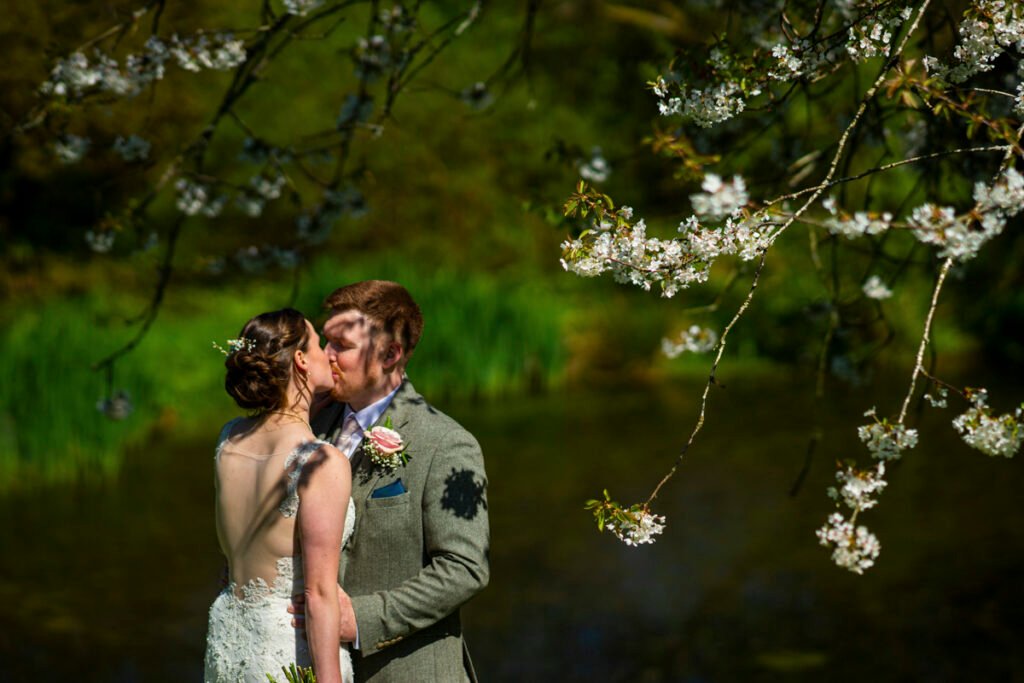 bride and groom kiss by the cherry blossom