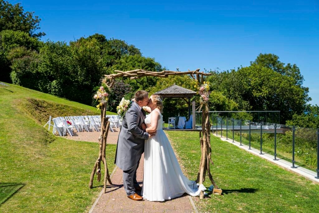 Bride and Groom kissing under Arch