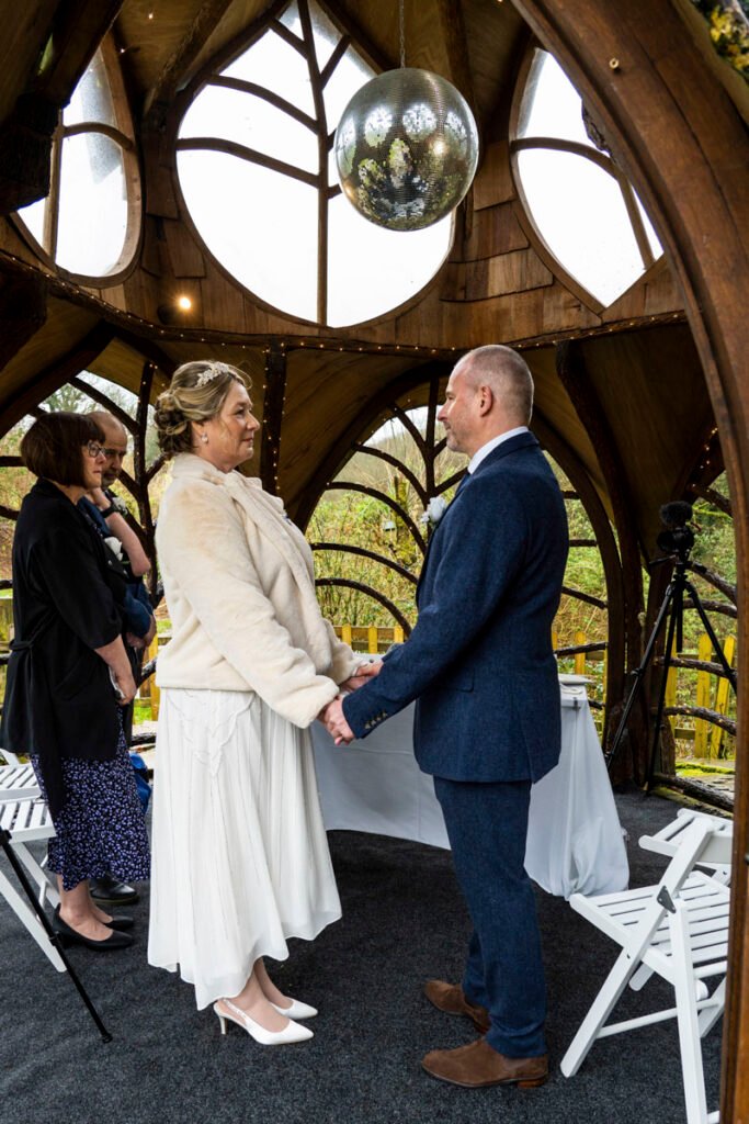 bride and groom exchanging vows during the wedding ceremony at St Nectans Glen ceremony wedding photographer in cornwal