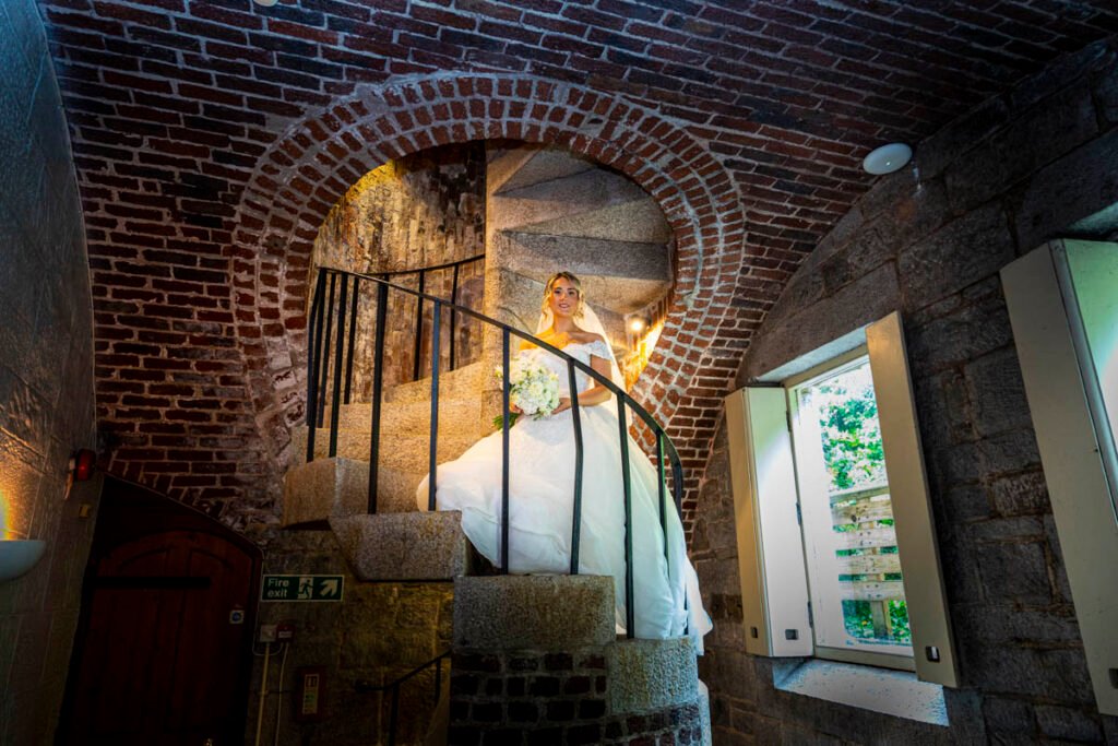 bride sitting on the spiral stairs at Polhawn Fort cornwall wedding venue