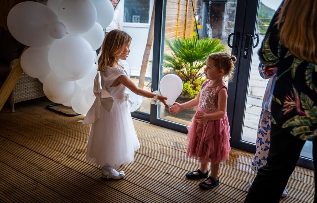flower girl and friend playing with balloons at Polhawn Fort cornwall wedding venue