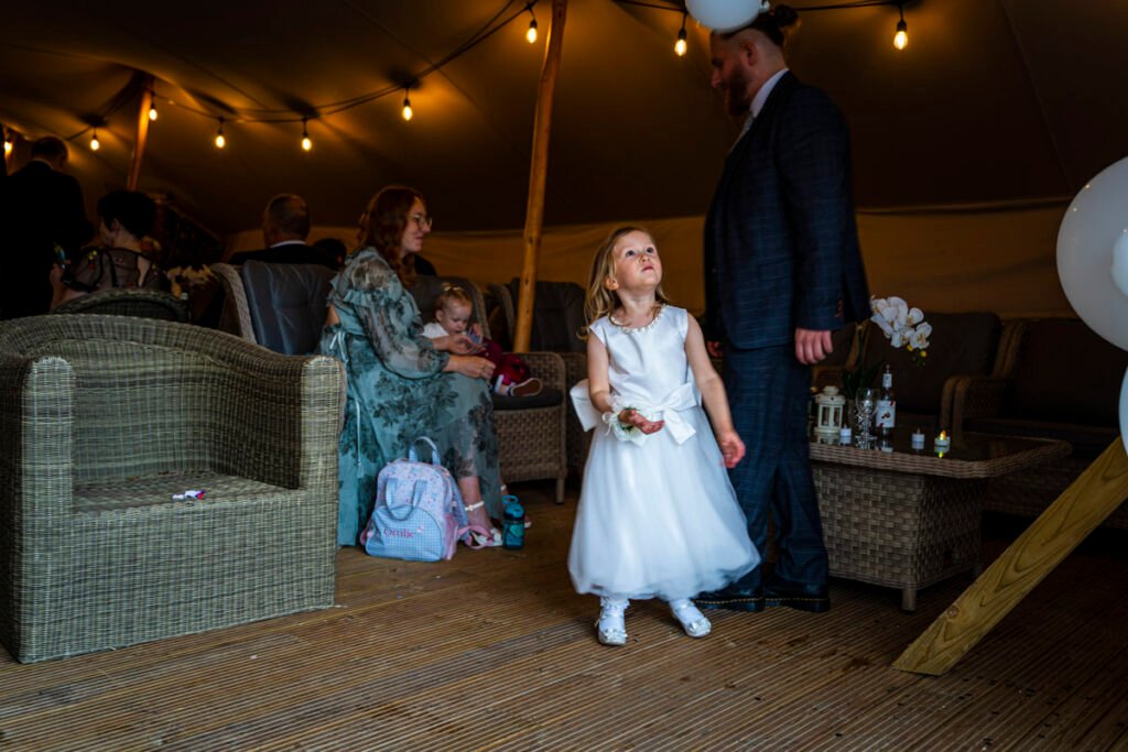 flower girl playing with balloons at Polhawn Fort cornwall wedding venue