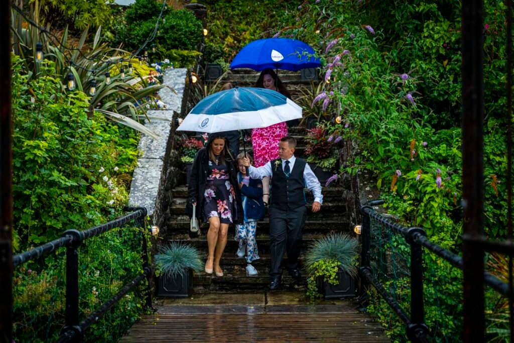 wedding guests arriving with umbrellas at Polhawn Fort cornwall wedding venue