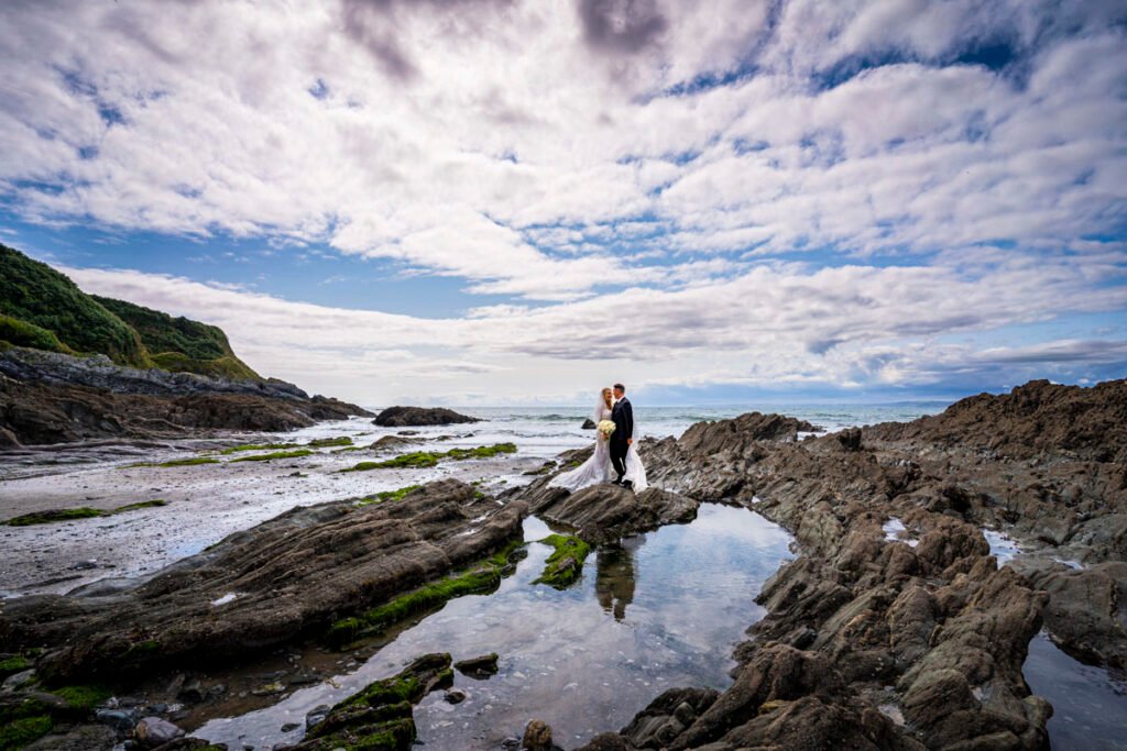 bride and groom reflected in a rock pool at Polhawn fort beach cornwall