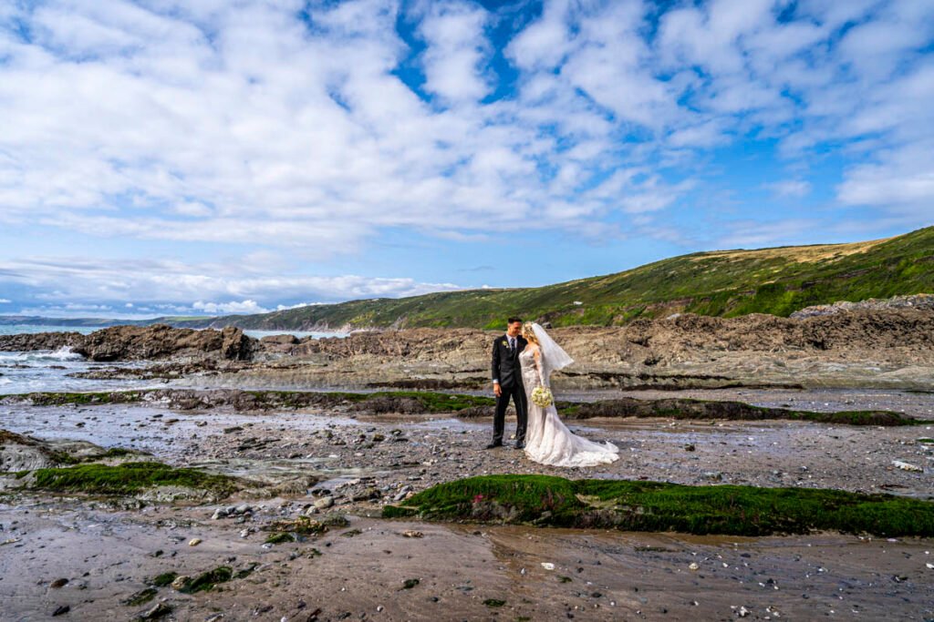 bride and groom walking on the beach at Polhawn fort cornwall