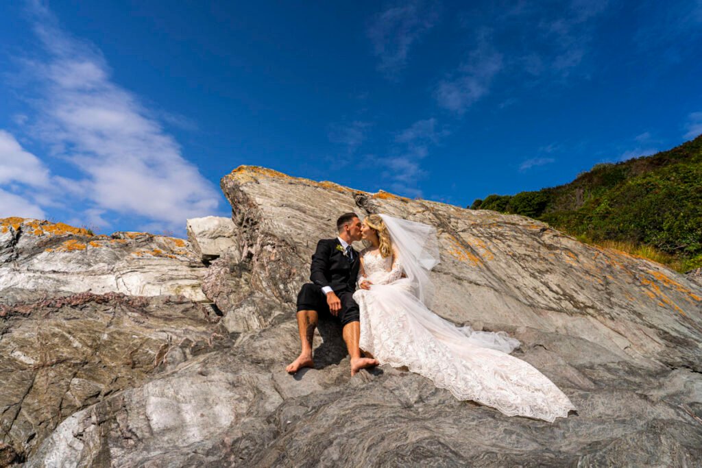 bride and groom kissing on the rocks at Polhawn fort cornwall