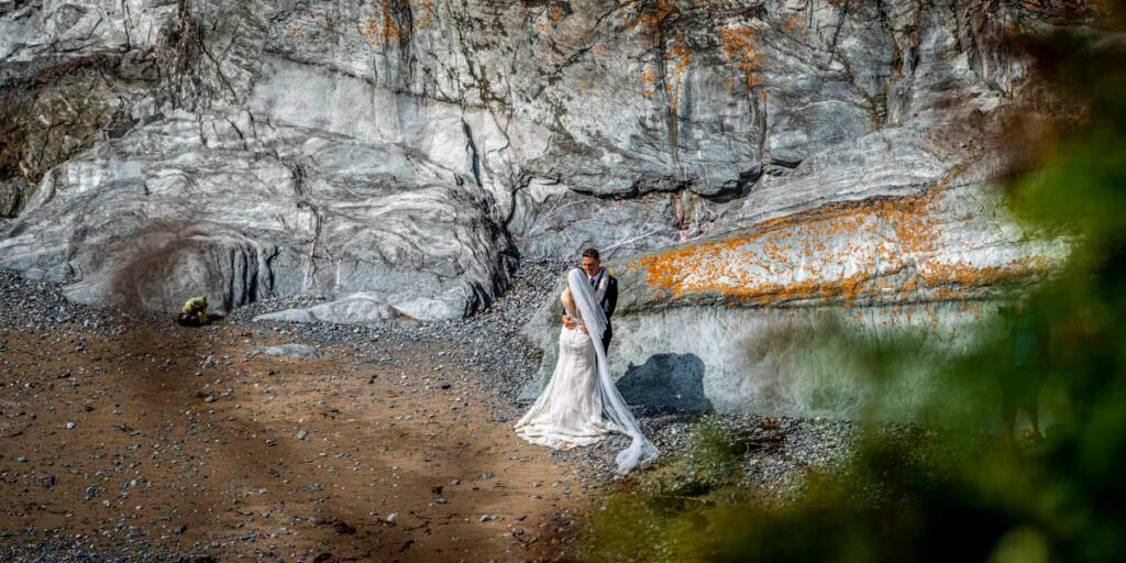 bride and groom overhead embrace on the beach at Polhawn fort cornwall