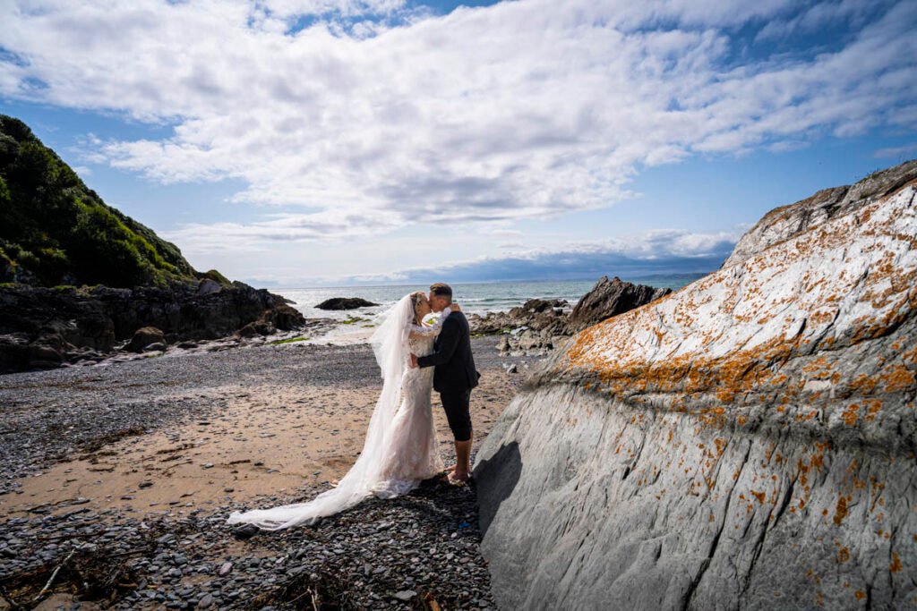 bride and groom kissing on the beach at Polhawn fort cornwall
