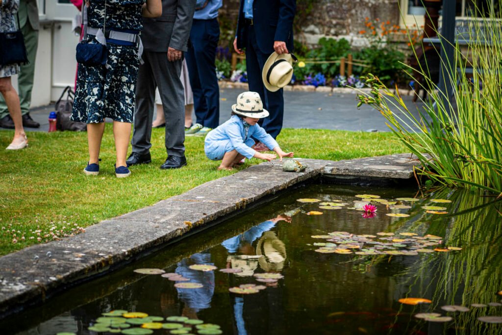 child reflected in the fish pond at an outdoor wedding