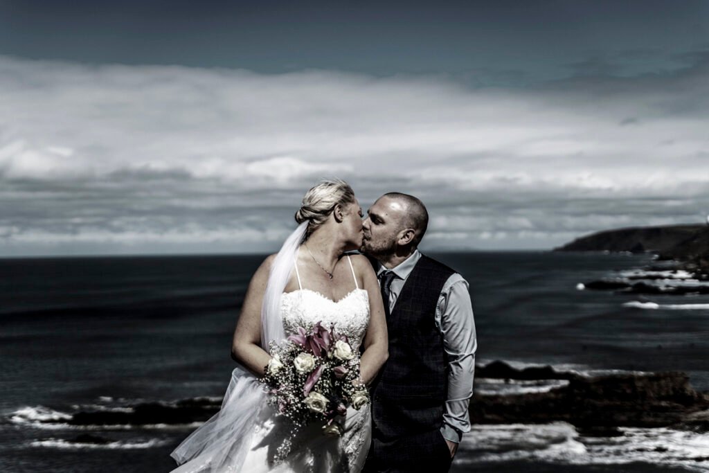 Bride and groom kiss on the cliffs sepia