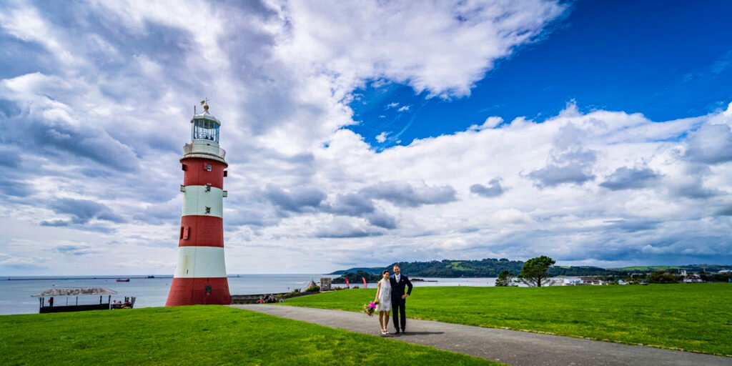 bride and groom embrace by Smeaton's Tower overlooking Plymouth Sound