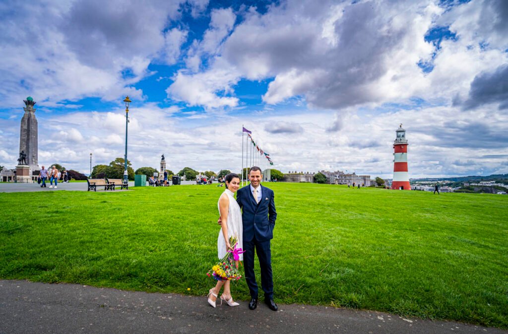 bride and groom in front of Smeaton's Tower overlooking Plymouth Sound