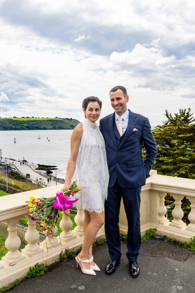 bride and groom embrace overlooking Plymouth Sound