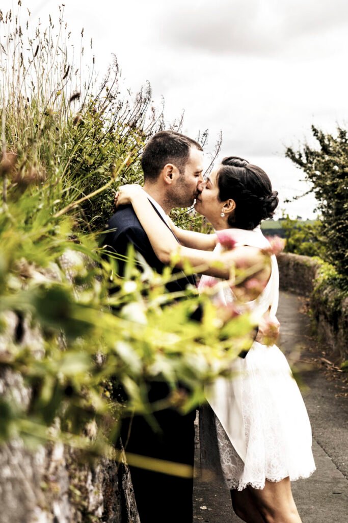 bride and groom kiss amongst flowers overlooking Plymouth Sound