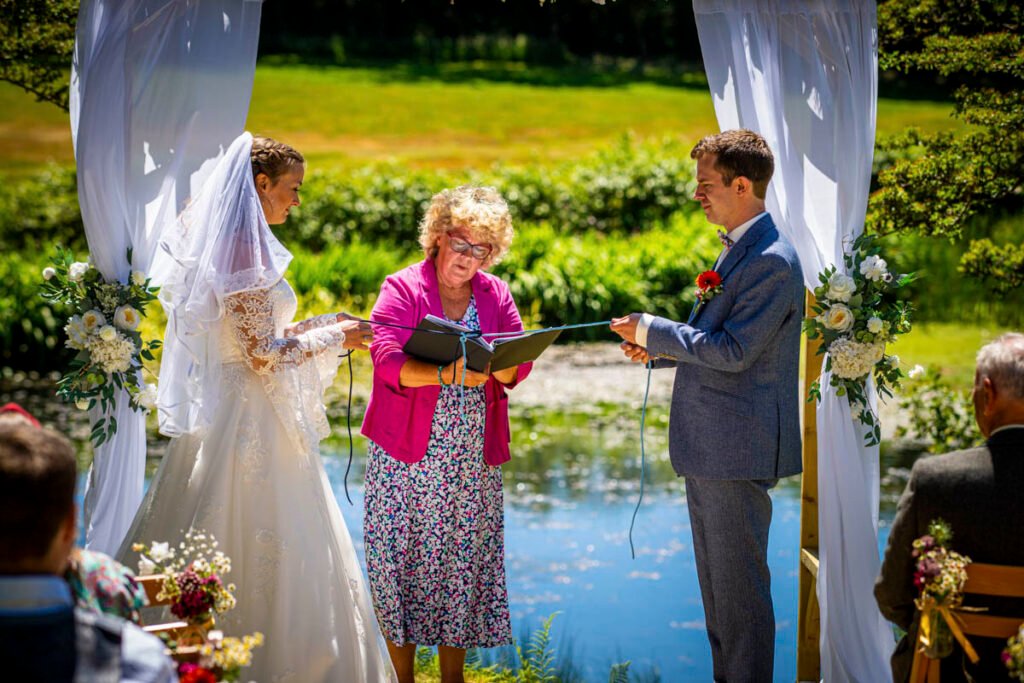 bride and groom hand fstening ceremony outdoors