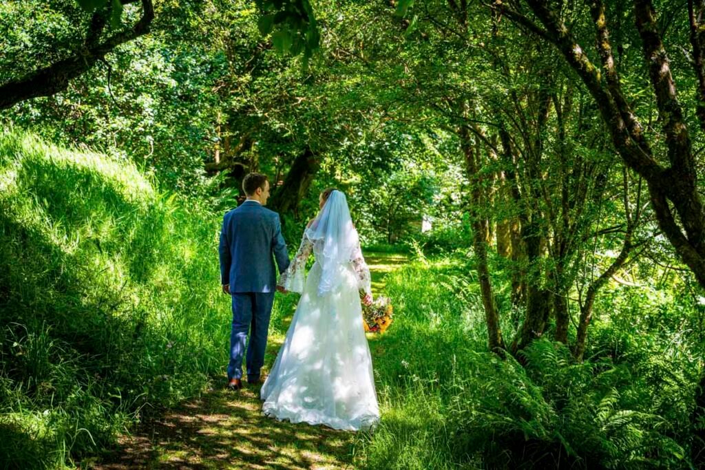 bride and groom walking in the woods at Ta Mill